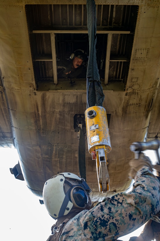 A ground team, composed of U.S. Marines with Combat Logistics Battalion (CLB) 3, 3rd Marine Logistics Group, hook simulated cargo to a CH-53E Super Stallion assigned to Marine Heavy Helicopter Squadron (HMH) 463, Marine Aircraft Group 24, during an external lift exercise, Dec. 10, 2019, Oahu, Hawaii. HMH-463 conducted an external lift exercise in conjunction with CLB 3 to increase readiness and familiarize both entities with external lift procedures. (U.S. Marine Corps photo by Sgt. Alex Kouns)