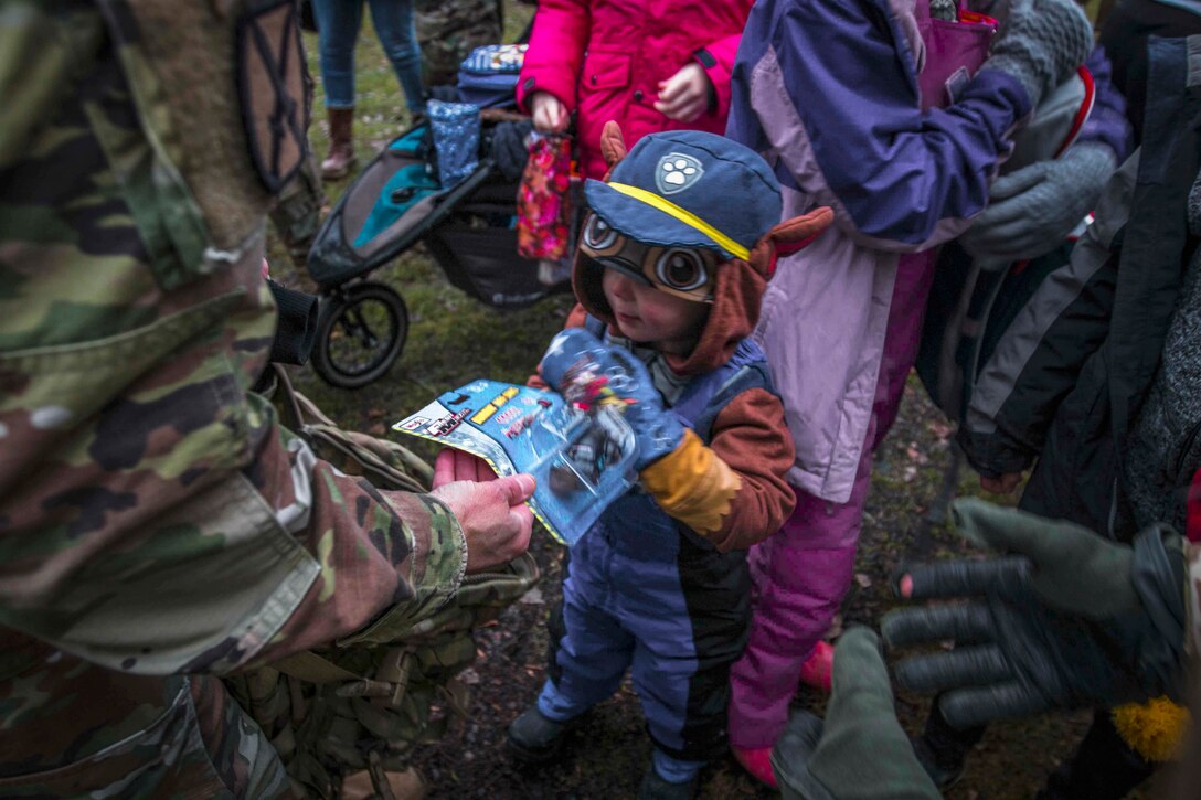 A soldier hands a toy to a child.