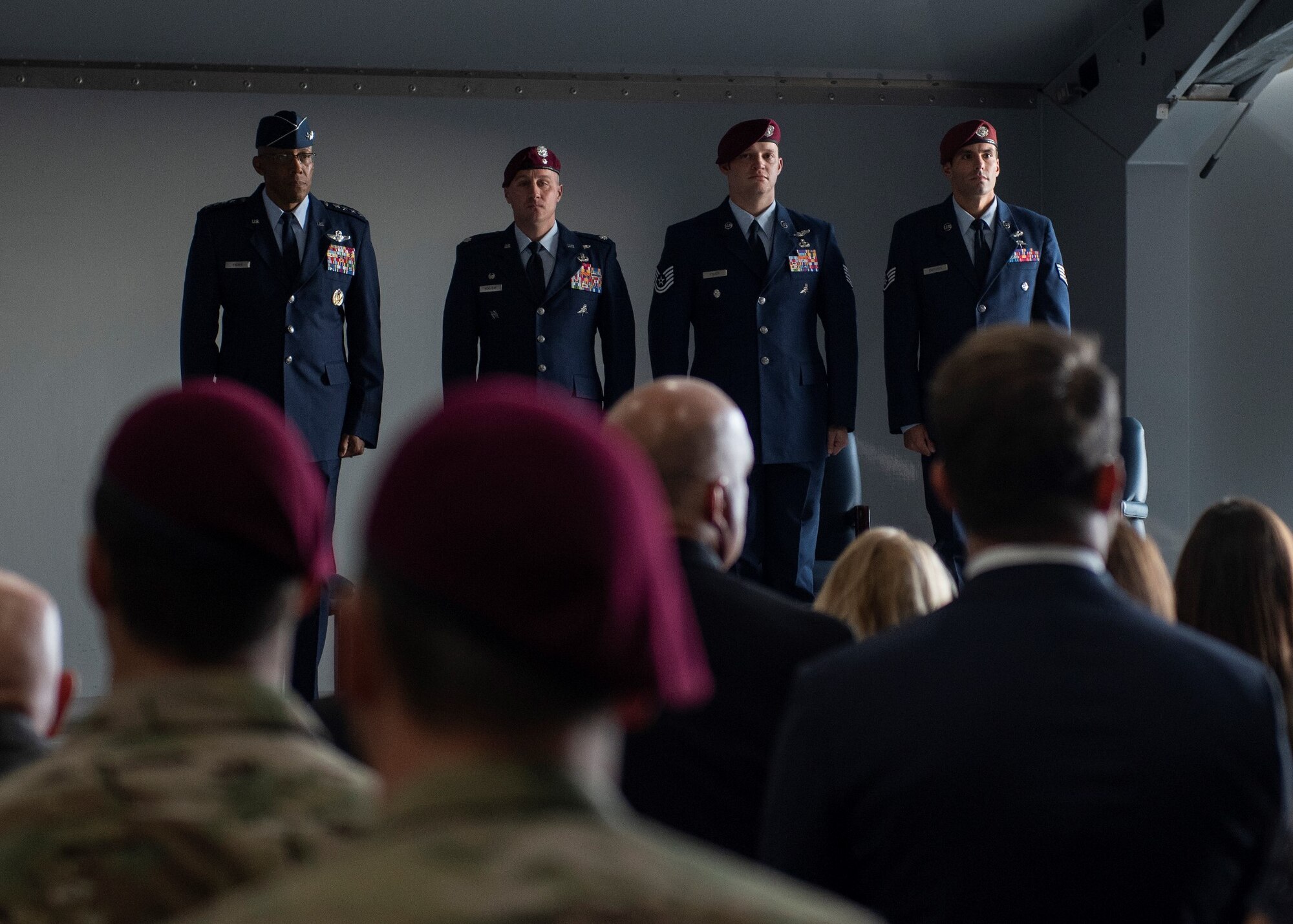 Four Airmen stand at attention in front of a crowd of people.