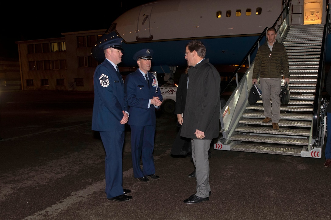 Defense Secretary Dr. Mark T. Esper speaks with two military officers outside an aircraft.