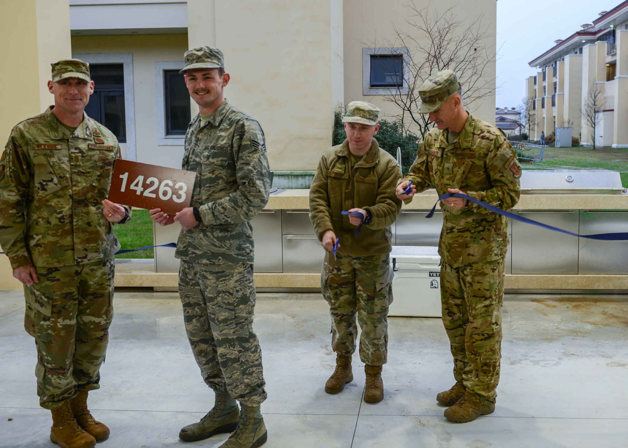 U.S. Air Force Brig. Gen. Daniel T. Lasica, 31st Fighter Wing commander, cuts a ribbon for the new dorm pavilion at Aviano Air Base, Italy, Dec. 13, 2019. The new pavilion offers a gas fire pit, two BBQ gas-grills, a projector and Bluetooth with surround sound for the Airmen to enjoy. (U.S. Air Force photo by Airman Thomas S. Keisler IV)