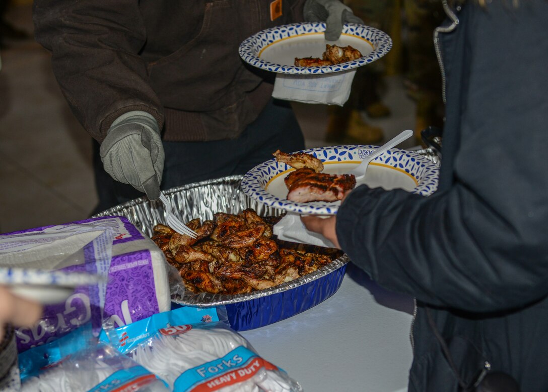 U.S. Air Force Airmen from the 31st Fighter Wing make a plate of ribs at Aviano Air Base, Italy, Dec. 13, 2019. Free BBQ, gelato, and hot chocolate were all provided at the grand opening ceremony for a new dorm pavilion. (U.S. Air Force photo by Airman Thomas S. Keisler IV)