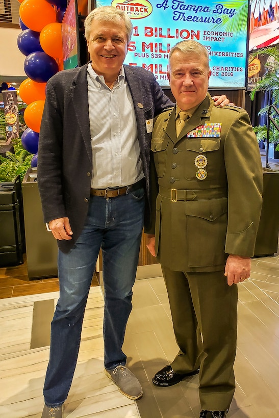 U.S. Marine Corps Gen. Kenneth F. McKenzie Jr., right, the commander of U.S. Central Command, and David Deno, left, Chief Executive Officer Bloomin’ Brands Inc., pose for a photo at Raymond James Stadium in Tampa, Florida, Dec. 12, 2019. (U.S. Army photo by CPT Jennifer Cruz)