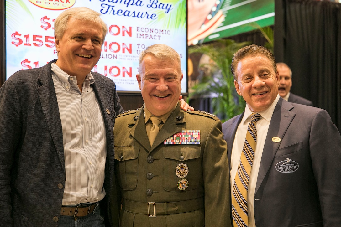 U.S. Marine Corps Gen. Kenneth F. McKenzie Jr., center, the commander of U.S. Central Command, David Deno, left, Chief Executive Officer Bloomin’ Brands Inc., and James P. McVay, Chief Executive Officer of the Outback Bowl, pose for a photo at Raymond James Stadium in Tampa, Florida, Dec. 12, 2019. (U.S. Marine Corps photo by Sgt. Roderick Jacquote)