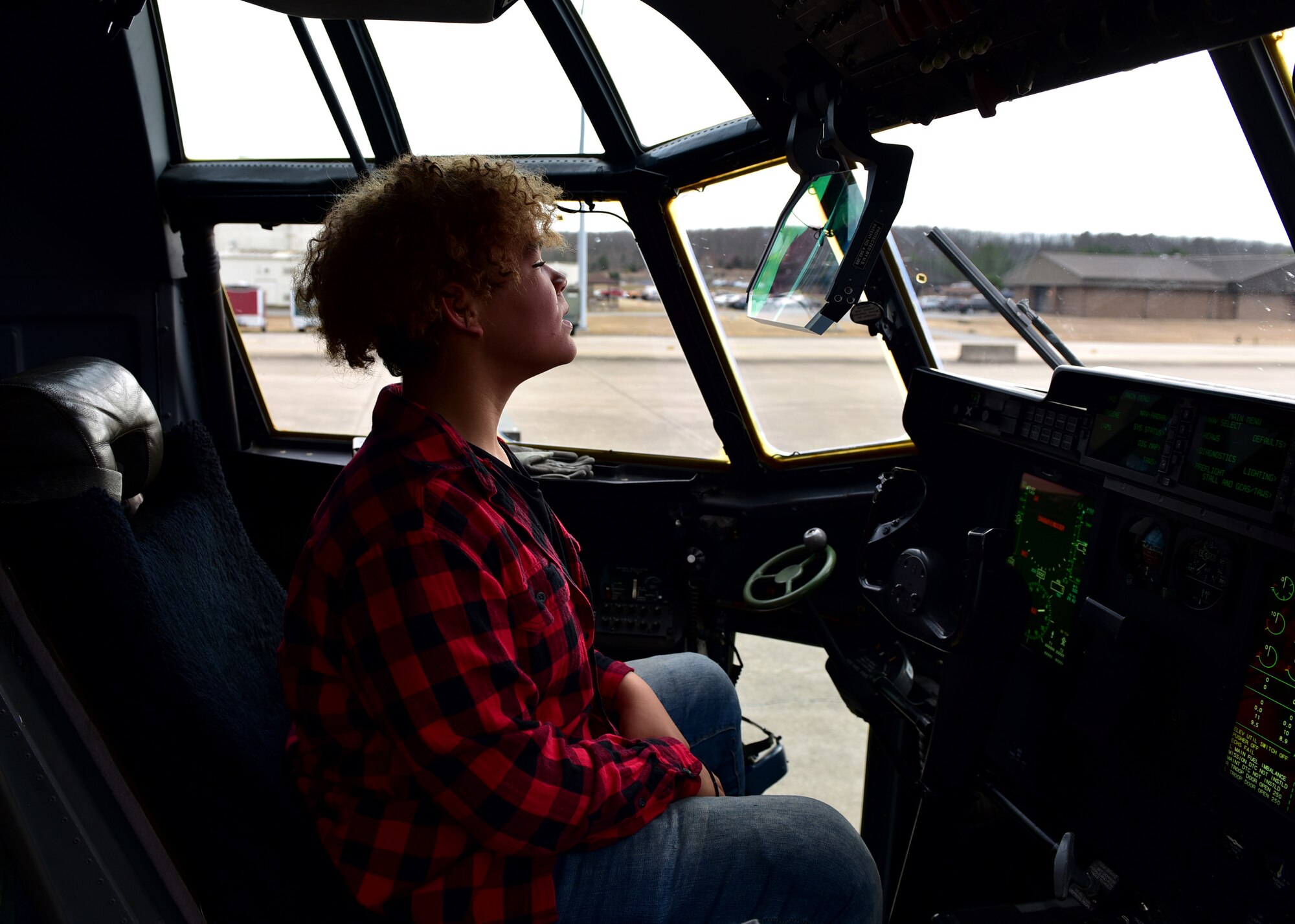 A student walks on a flight line and sits in a large aircraft