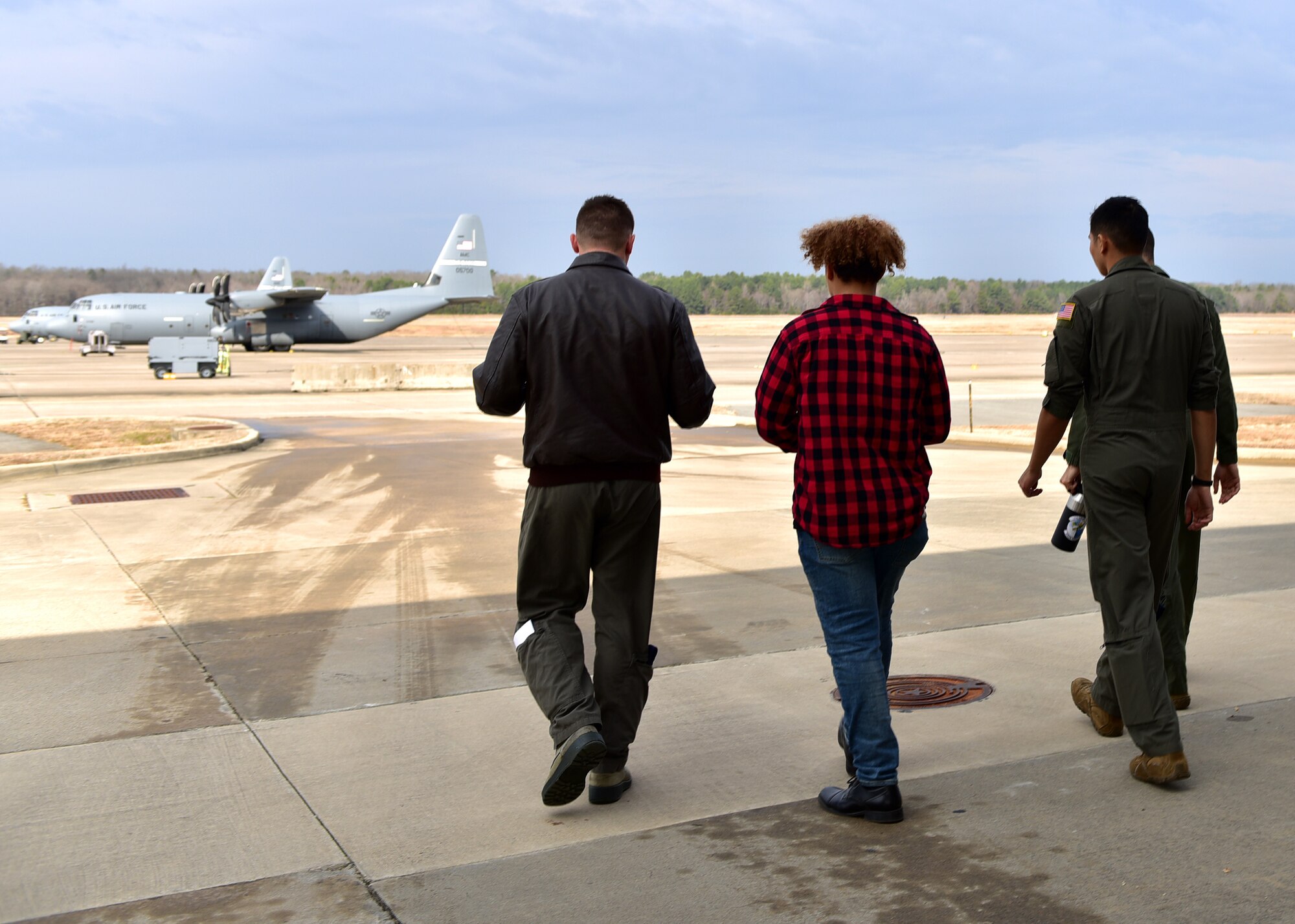 A student walks on a flight line and sits in a large aircraft