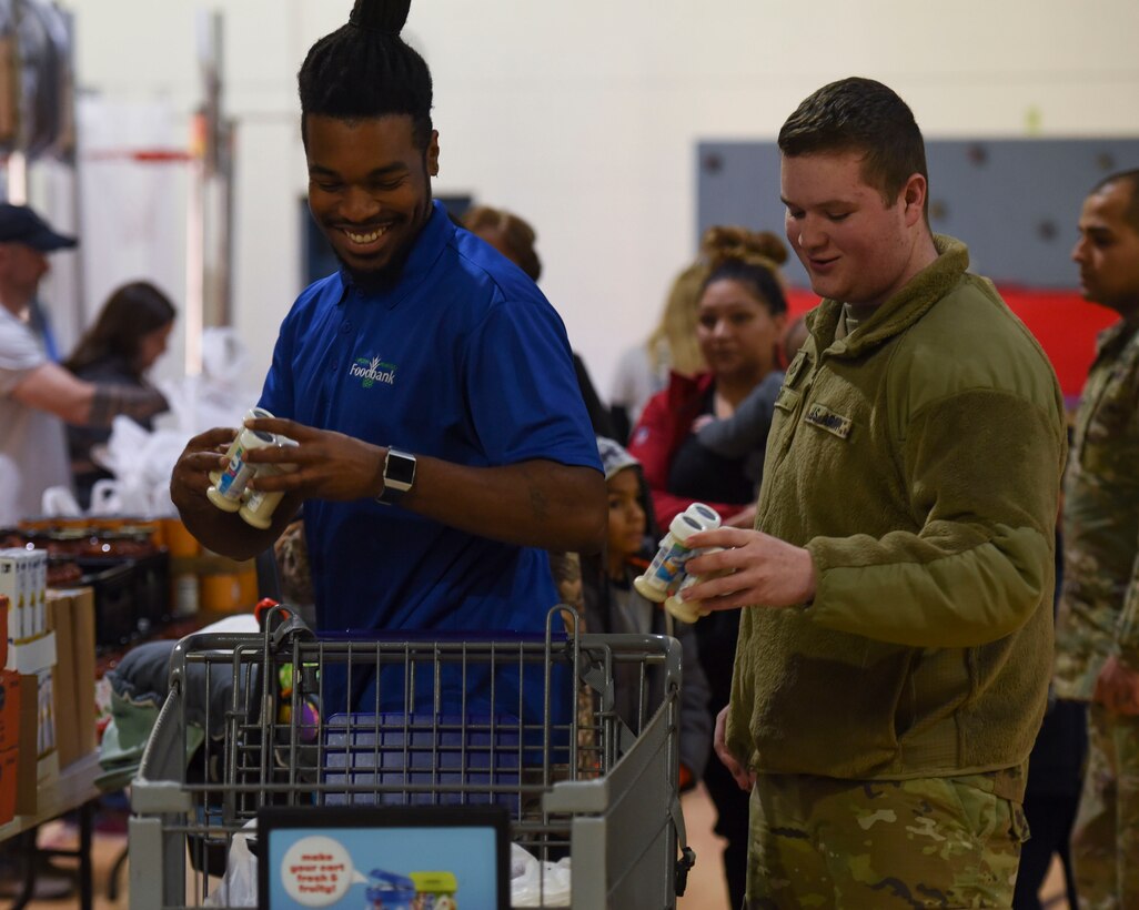 Andrew Council, Virginia Peninsula Foodbank product manager, and U.S. Army Pfc. Daniel Smith, 331st Transportation Company, 11th Battalion, 7th Transportation Brigade allied trade specialist, put groceries in a cart during a holiday food distribution at Joint Base Langley-Eustis, Virginia, Dec. 11, 2019.