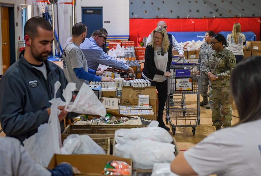 Event volunteers distribute groceries to participants during a holiday food distribution at Joint Base Langley-Eustis, Virginia, Dec. 11, 2019