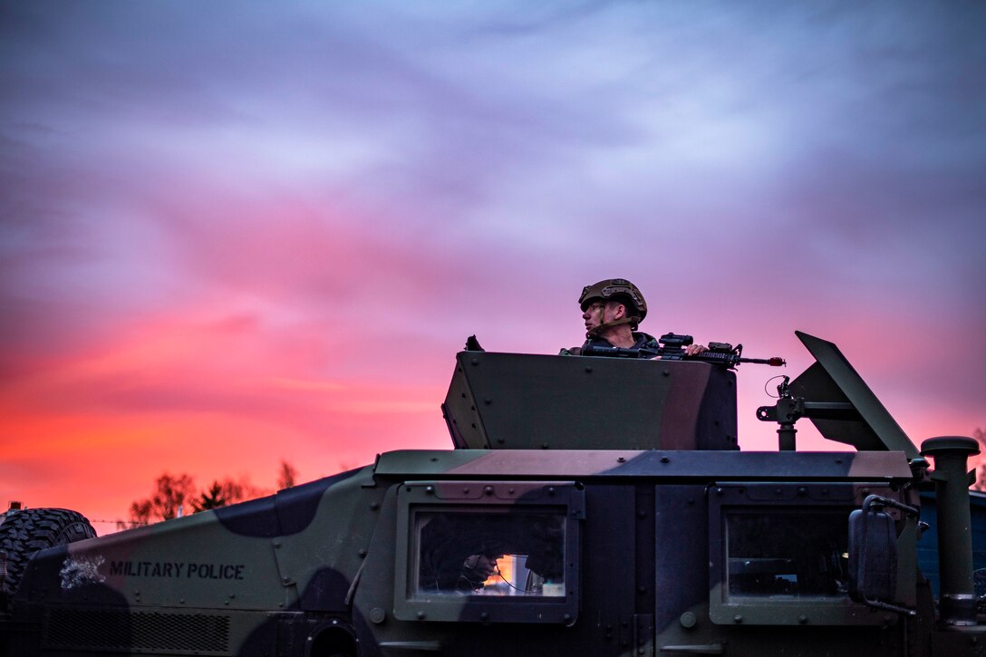 An airman rides in a military vehicle.