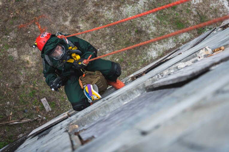 A service member repels down the side of a building.