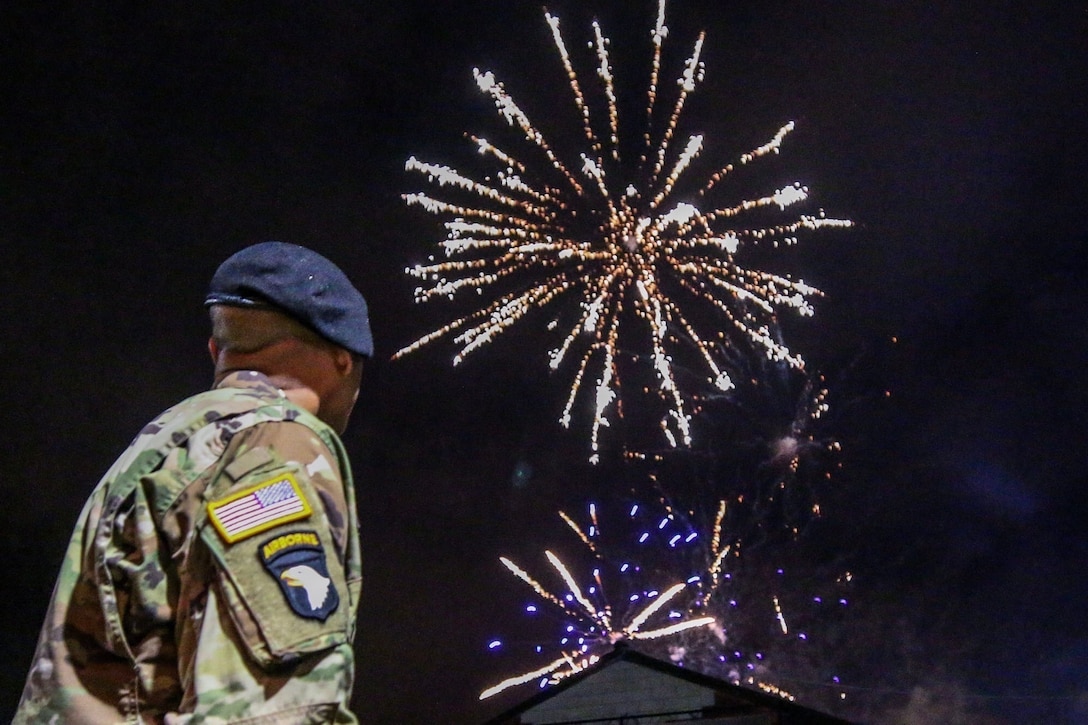 A soldier looks skyward to watch a fireworks display