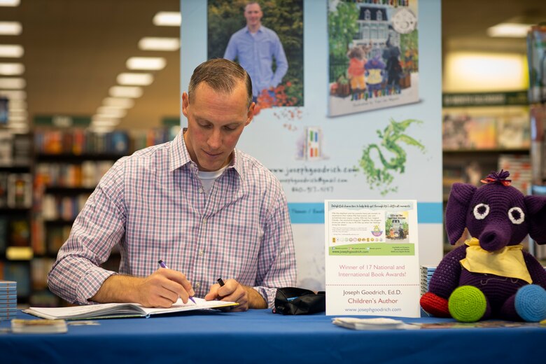 Marine Maj. Joseph Goodrich signs his book during his book-signing in Jacksonville, North Carolina, Nov. 30, 2019. Goodrich, now a published author, read his book to fans and signed copies of his book for young readers. Goodrich is the executive officer of Marine Aerial Refueler Transport Squadron 252. (U.S. Marine Corps photo by Cpl. Cody Rowe)