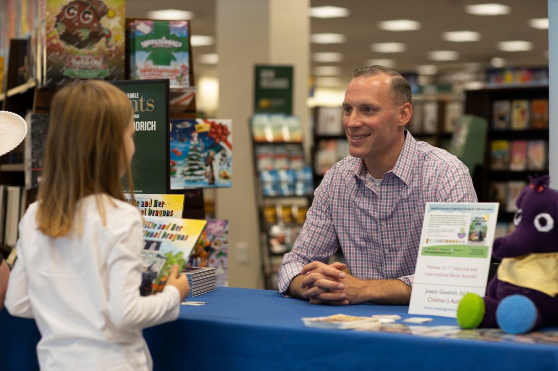 Marine Maj. Joseph Goodrich speaks to a young reader in Jacksonville, North Carolina, Nov. 30, 2019. Goodrich, now a published author, read his book to fans and signed copies of his book for young readers. Goodrich is the executive officer of Marine Aerial Refueler Transport Squadron 252. (U.S. Marine Corps photo by Cpl. Cody Rowe)