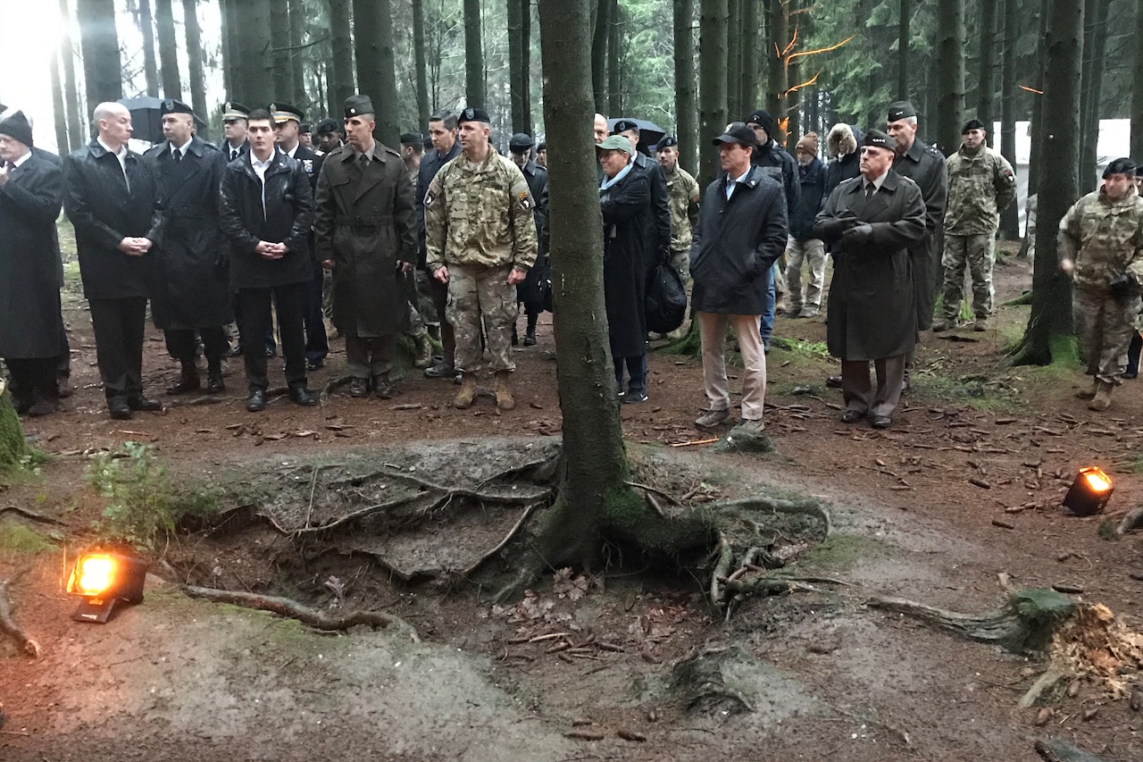 Civilians and military personnel view a World War II battle site.