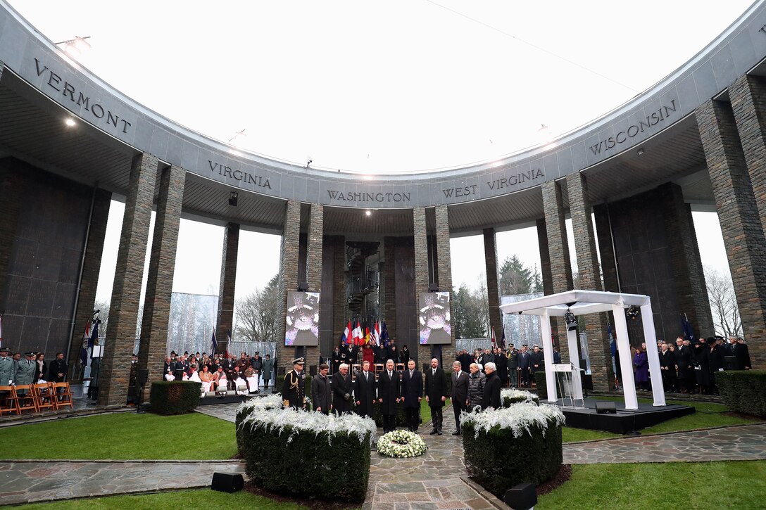 A group of men stand in a semi-circle around a wreath.