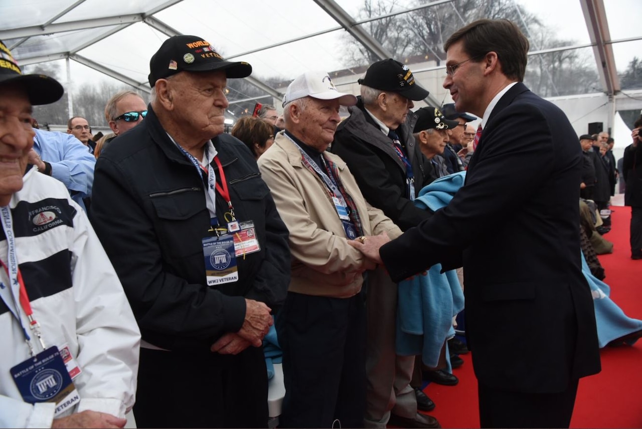 A man shakes hands with a line of WWII veterans.