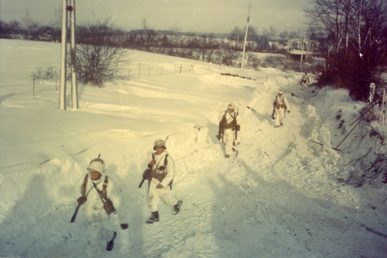 Soldiers walk through the snow.