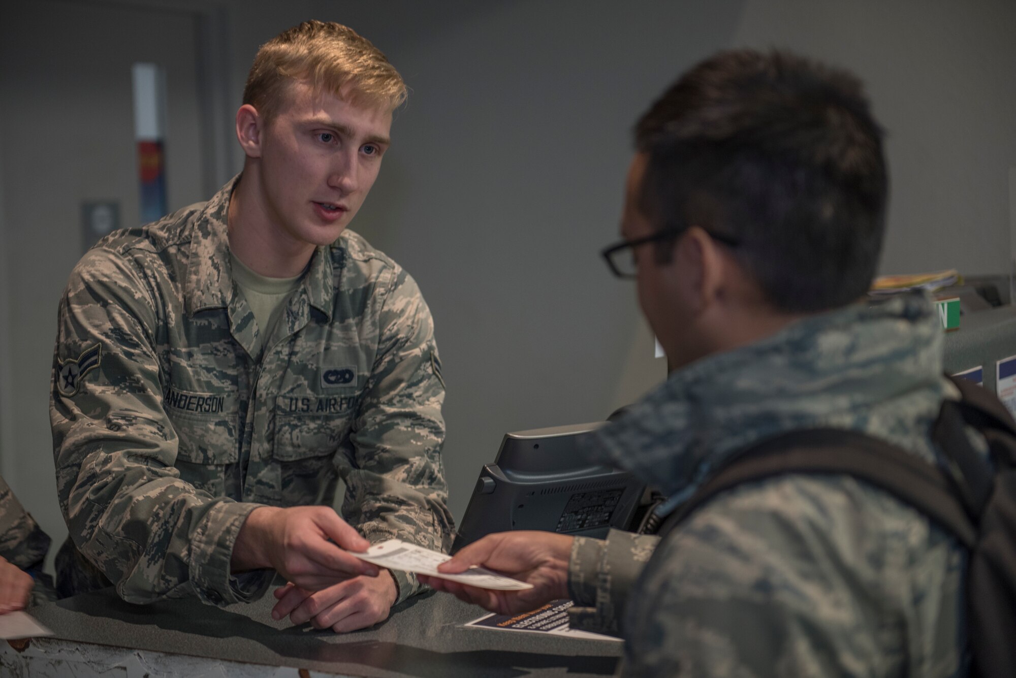 U.S. Air Force Airman 1st Class Morgan Anderson, 60th Aerial Port Squadron air transportation agent, hands Staff Sgt. Christopher Andino Fuentes, 349th maintenance Squadron aerospace ground equipment maintainer, his boarding ticket Dec. 6, 2019, at Travis Air Force Base, California. Anderson manned the roll call counter to take passengers’ bags and give them their tickets. (U.S. Air Force photo by Airman 1st Class Cameron Otte)