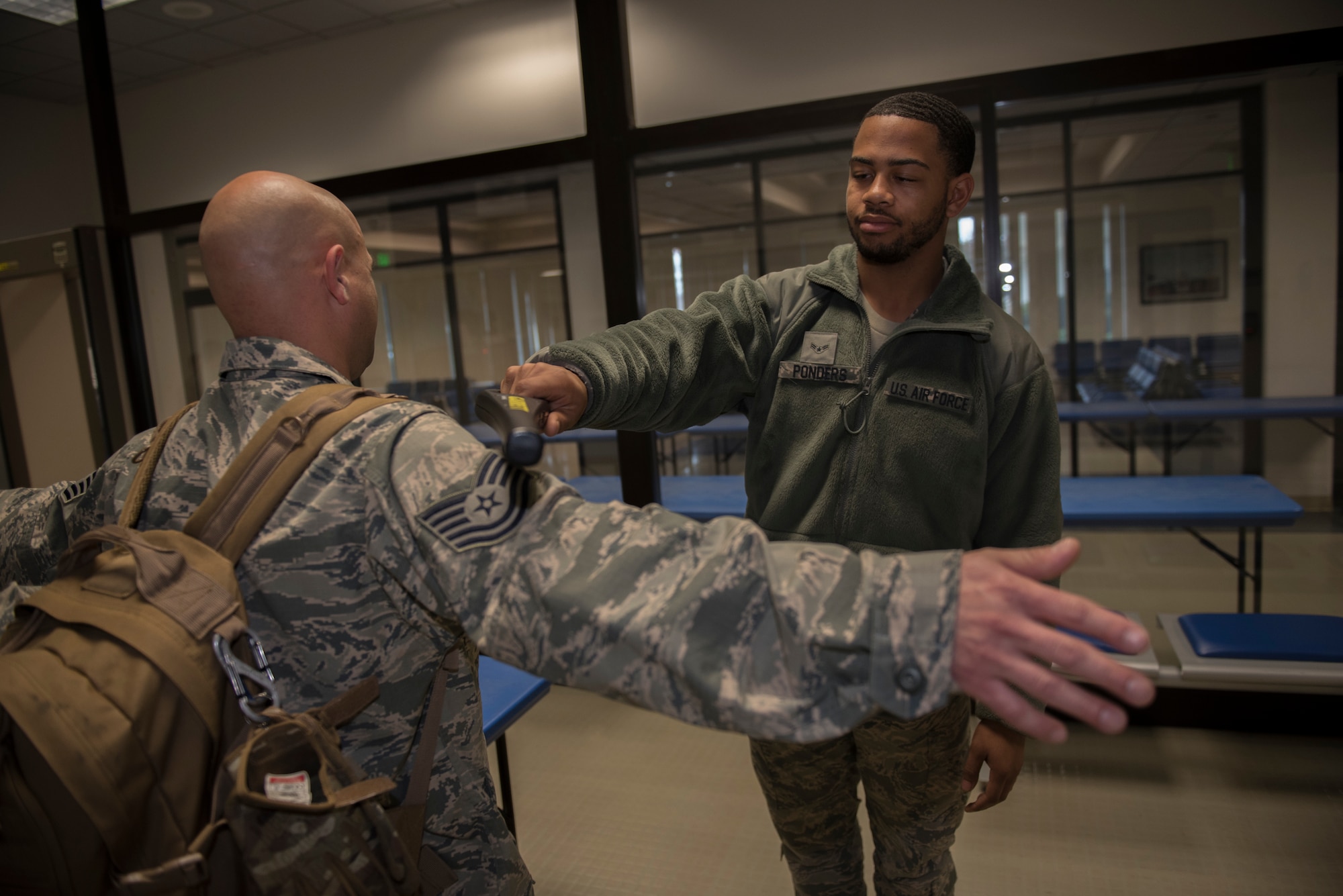 U.S. Air Force Airman 1st Class Damien Penders, 60th Aerial Port Squadron air transportation agent, uses a Garret Super Wand to scan Tech. Sgt. Andrew Purcell, 945th Aircraft Maintenance Squadron crew chief, for any prohibited items Dec. 6, 2019, at Travis Air Force Base, California. Penders scanned people who set off the alarm on the magnetometer to double check they have no prohibited items. (U.S. Air Force photo by Airman 1st Class Cameron Otte)