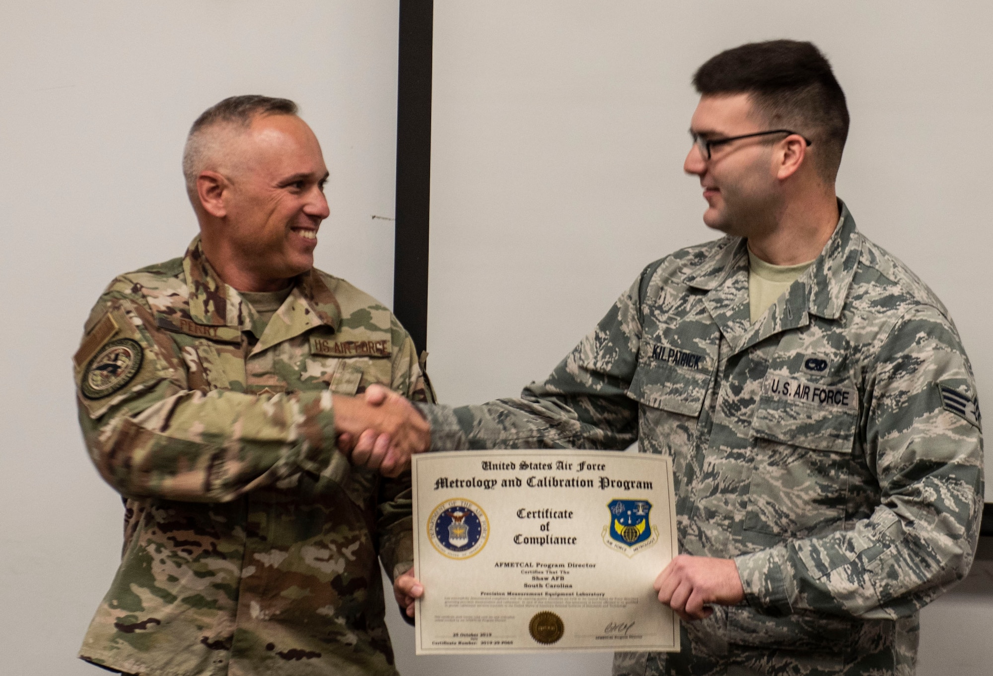 U.S. Air Force Chief Master Sgt. Jason Perry, Air Combat Command functional manager, left, presents Senior Airman Joshua Kilpatrick, the 20th Component Maintenance Squadron (CMS) physical dimensional technician, with the Air Force Metrology and Calibration (AFMETCAL) certificate at Shaw Air Force Base, South Carolina, Dec. 5, 2019.