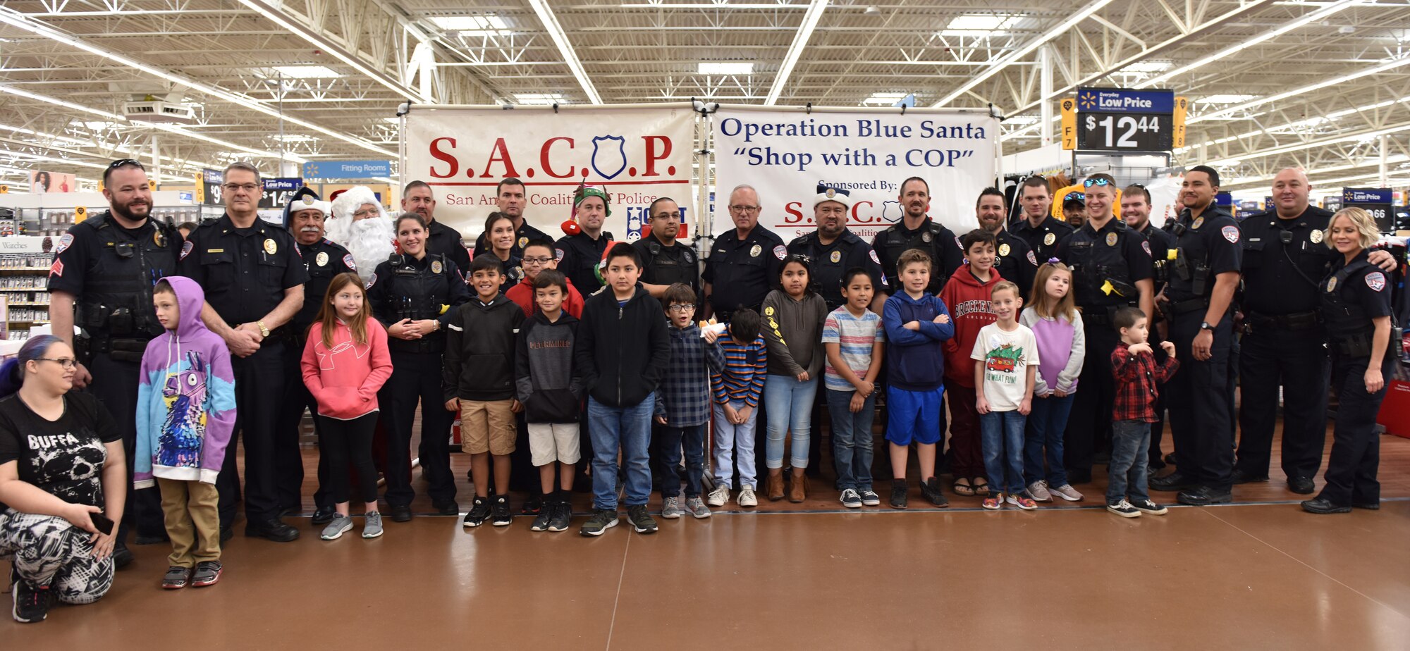Participants and volunteers at the Operation Blue Santa Shop with a Cop event in San Angelo, Texas, stand for a group photo before beginning shopping Dec. 14, 2019. After shopping volunteers also wrapped any presents for the participants. (U.S. Air Force photo by Senior Airman Seraiah Wolf)