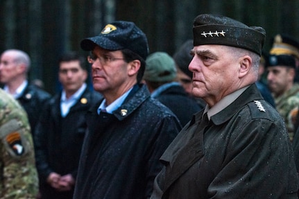 Defense secretary and Joint Chiefs chairman visit a site from World War II’s Battle of the Bulge. Their hats are wet with rain.