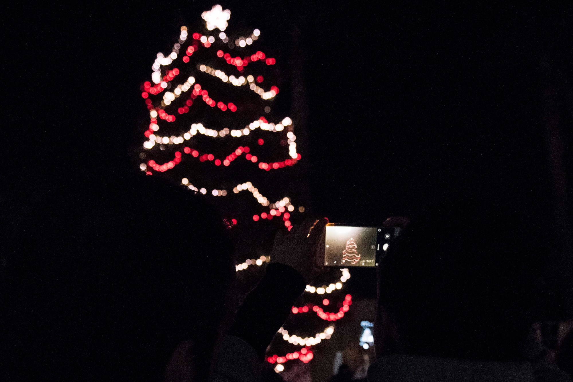 A community member takes a picture of the base Christmas tree Dec. 5, 2019, at Incirlik Air Base, Turkey. The 39th Air Base Wing hosted a tree lighting event to kick off the holiday season at Incirlik. (U.S. Air Force photo by Staff Sgt. Joshua Magbanua)