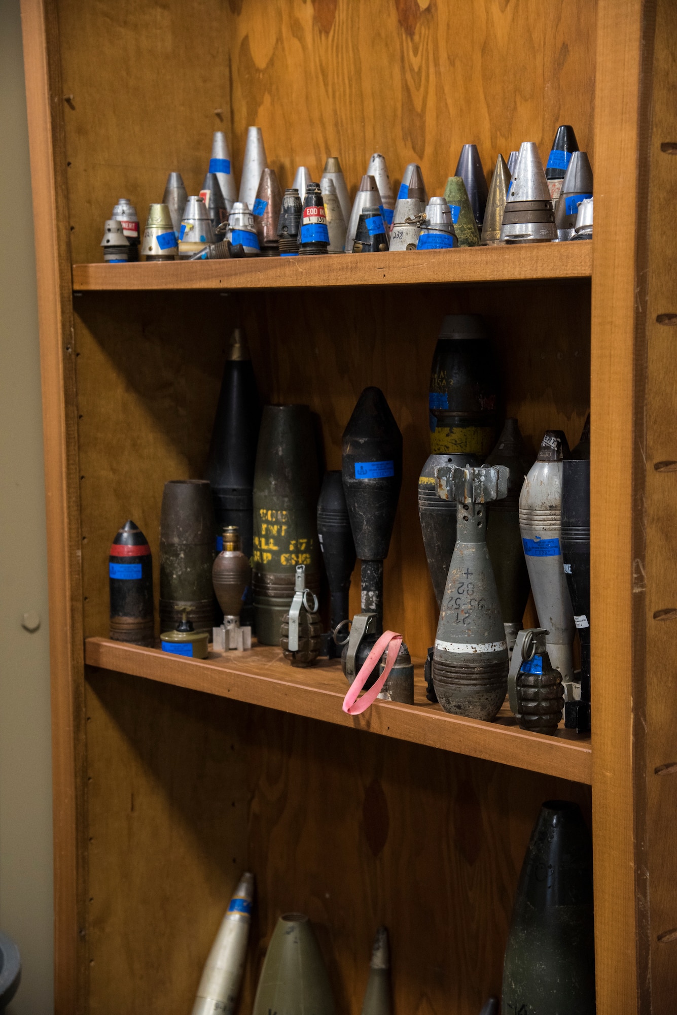 A shelf of various disarmed explosives sits on display.