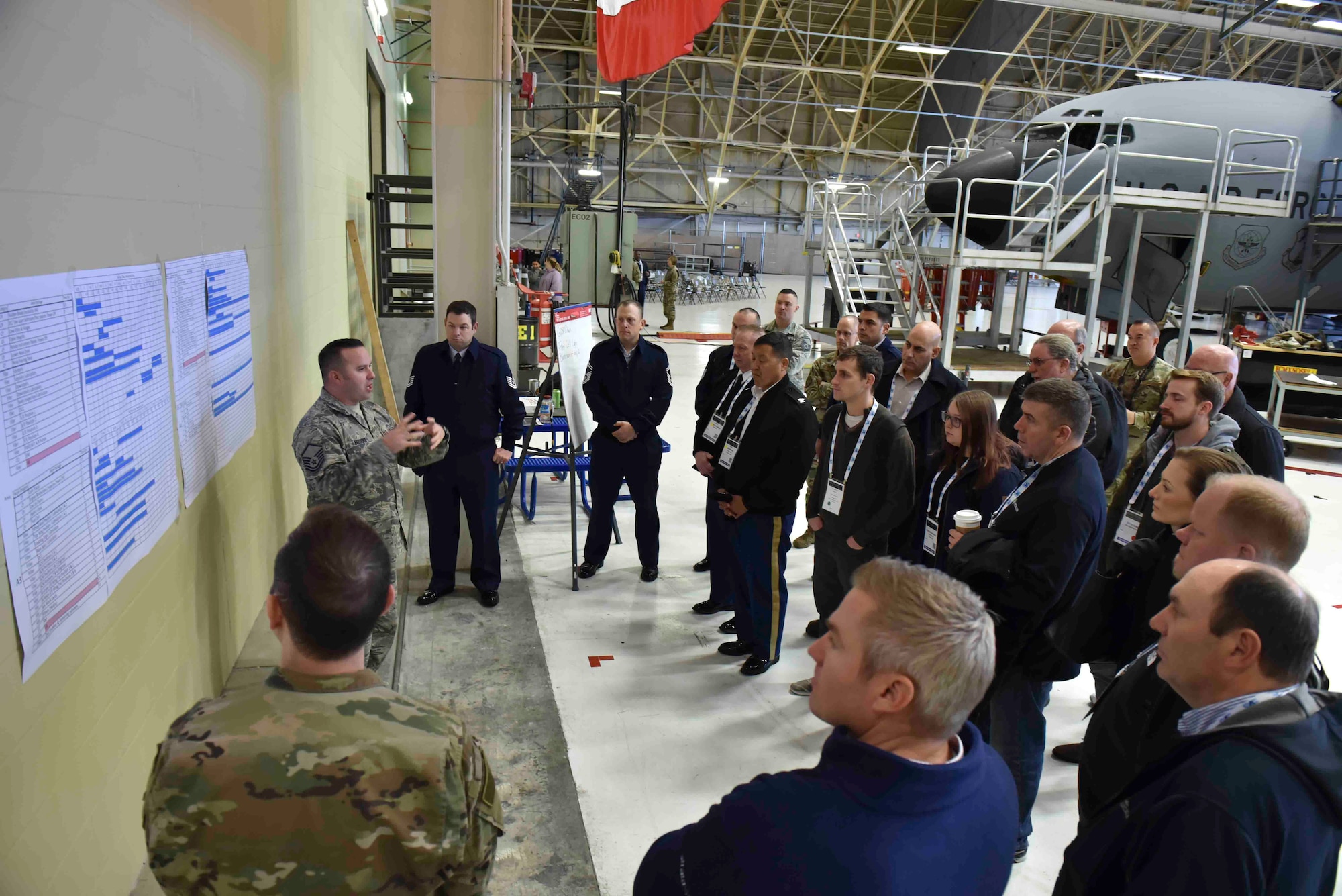 U.S. Air Force Master Sgt. Derrick Brooke, 92nd Maintenance Squadron periodic inspection chief, explains to members from the Department of Defense Maintenance Symposium how Team Fairchild implemented Theory of Constraints at Fairchild Air Force Base, Washington, Dec 12, 2019. TOC is a management process that enables Airmen to work efficiently and quickly, cutting time spent on inspections and costs. (U.S. Air Force photo by Airman 1st Class Kiaundra Miller)