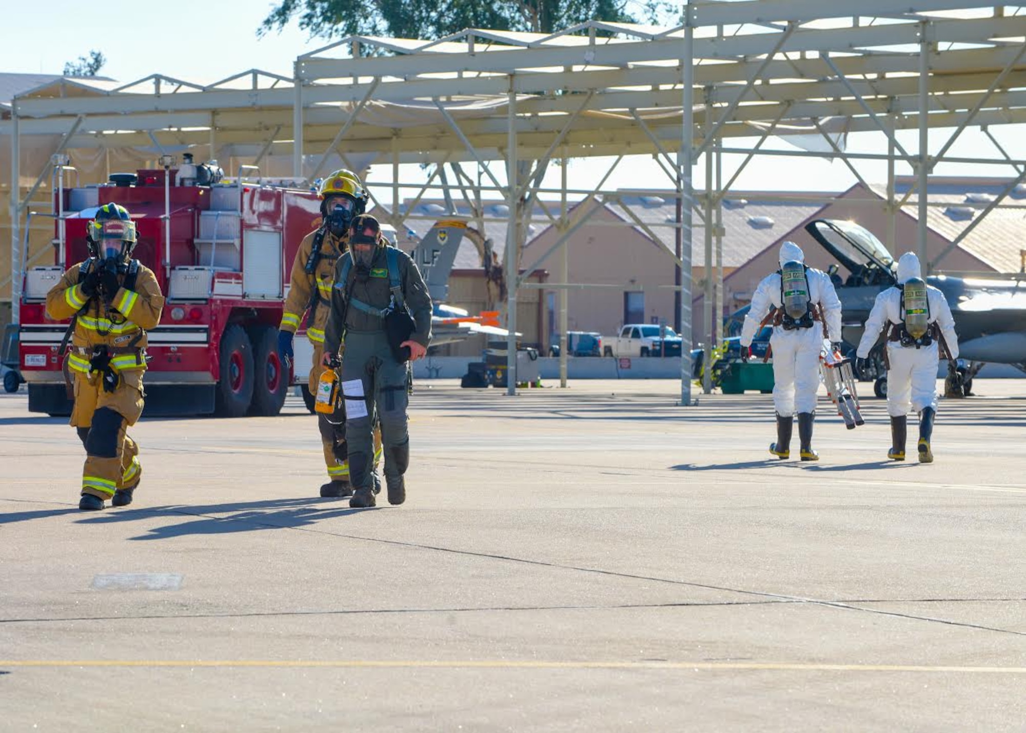 Luke Air Force Base firefighters escort a pilot away from an F-16C Fighting Falcon while 56th Maintenance Group aircraft fuels specialists respond to a ground emergency Dec. 9, 2019, at Luke Air Force Base, Ariz.
