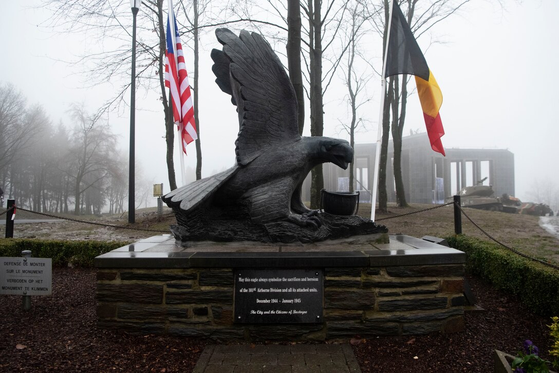 A monument  featuring a large bird and a flag is seen in the fog.
