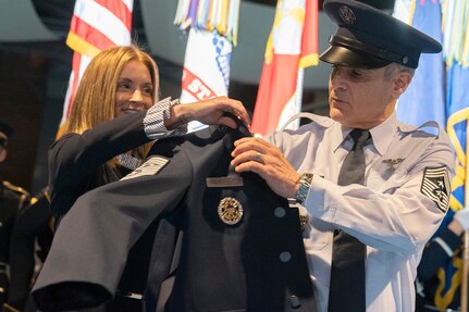 Janet Colon-Lopez, wife of Senior Enlisted Advisor to the Chairman Ramon "CZ" Colon-Lopez, helps her husband put on his new jacket during a change of responsibility cermony at Conmy Hall, Joint Base Myer-Henderson Hall, Virginia, Dec. 13.