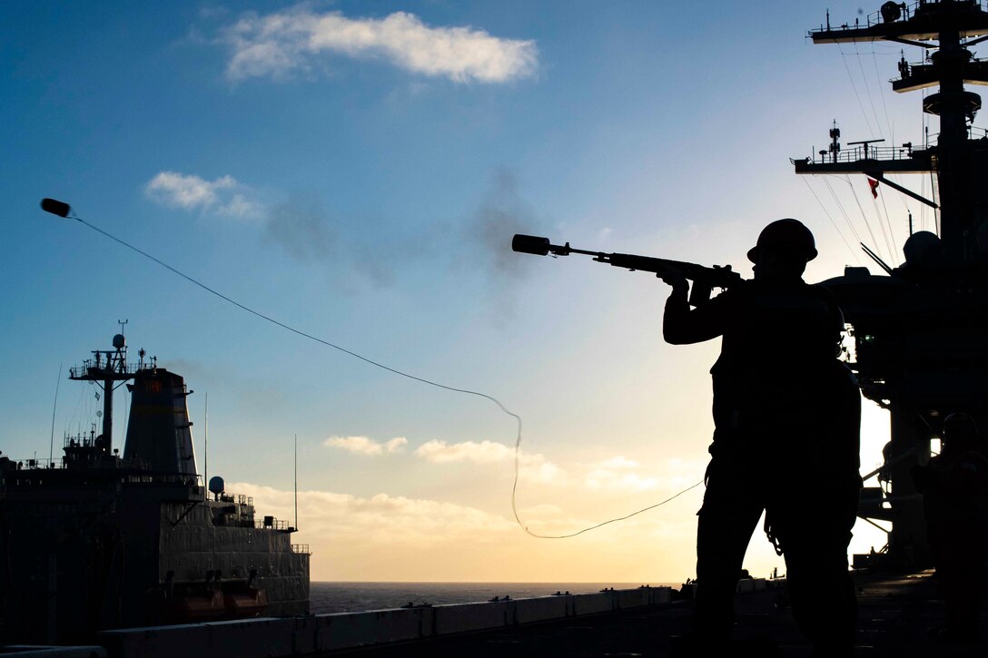 A sailor fires a shot line.