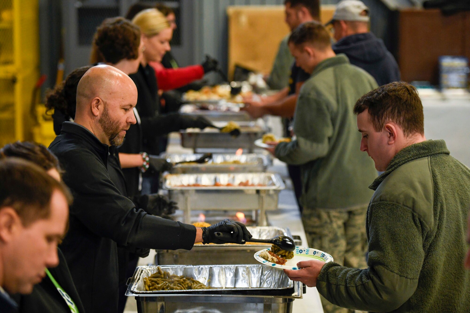 Volunteers serve food during the Feed the Troops (FTT) event at Dover Air Force Base, Del., Dec. 17, 2019. Volunteers from the local community prepared 45 turkeys and other fixings to feed more than 1,000 Airmen and family members. (U.S. Air Force photo by Senior Airman Eric M. Fisher)