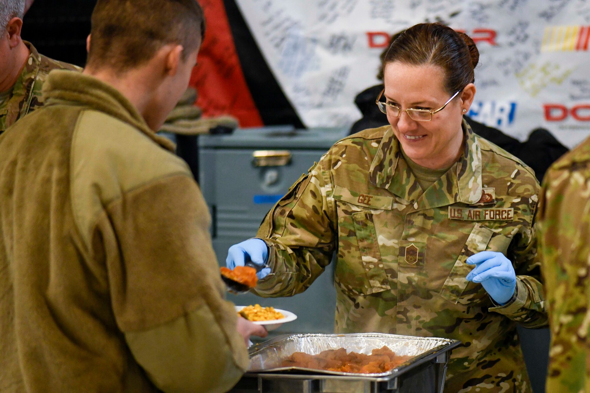 Chief Master Sgt. Shae Gee, 436th Airlift Wing command chief, serves food during the Feed the Troops event at Dover Air Force Base, Del., Dec. 17, 2019. Volunteers from the local community prepared 45 turkeys and other fixings to feed more than 1,000 Airmen and family members. (U.S. Air Force photo by Senior Airman Eric M. Fisher)