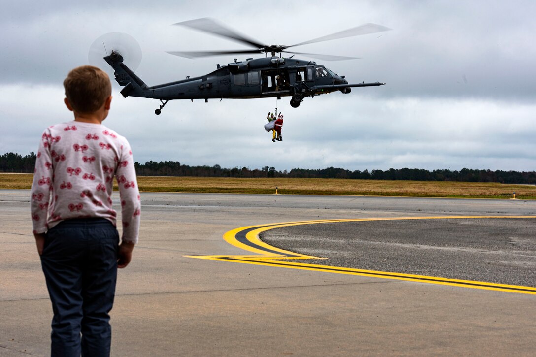 A photo of a participant watching Santa and his elf get lowered from an HH-60G Pave Hawk.