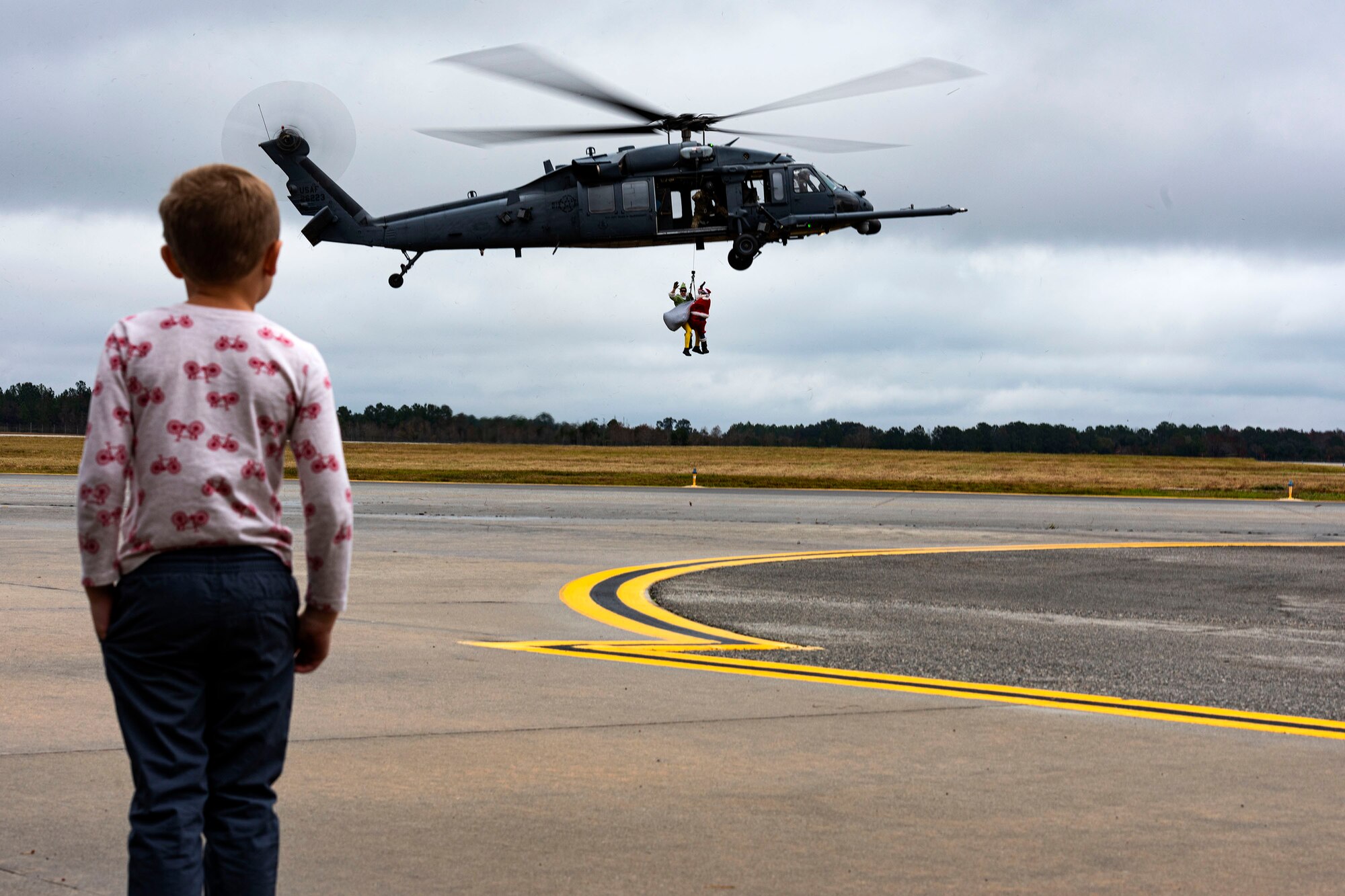 A photo of a participant watching Santa and his elf get lowered from an HH-60G Pave Hawk.