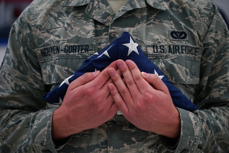 Airman 1st Class Cody Nguyen-Gorter, base honor guardsman, holds a U.S. flag during a ceremony for disposal of unserviceable flags Dec. 7, 2019, on Grand Forks Air Force Base, North Dakota. Nguyen-Gorter was joined by fellow honor guardsmen and a local American Legion post for the ceremony, which was followed by the burning of nearly 50 faded, worn or otherwise unserviceable flags which served their lives in the Grand Forks community. (U.S. Air Force photo by Senior Airman Elora J. Martinez)