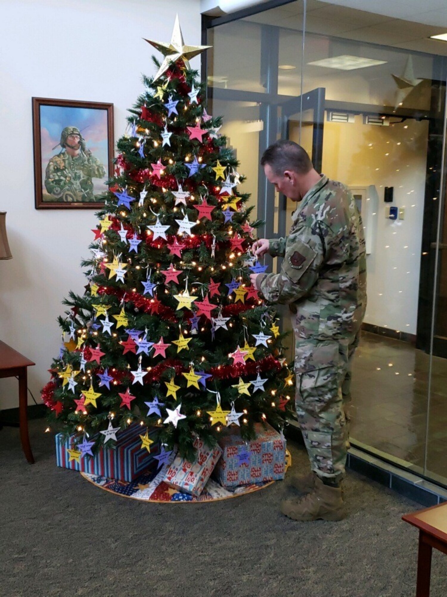 One person standing, placing a star on a Christmas tree.