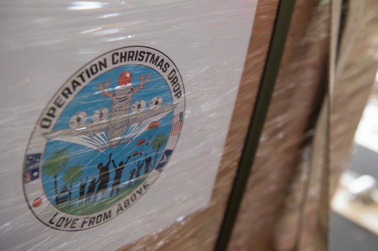 A logo reading "Operation Christmas Drop - Love From Above" adorns a large brown box.
