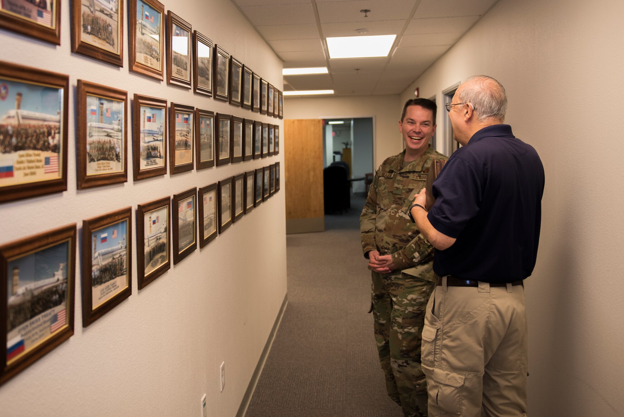 Sal Pampinella, right, International Treaty Compliance Office staff member, shares a laugh with Col. Jeffrey Nelson, left, 60th Air Mobility Wing commander, Dec. 13, 2019, at Travis Air Force Base, California. Pampinella manages and directs all activities that involve foreign visitors. Nelson toured the International Treaty Compliance Office as part of the Leadership Rounds, a program that allows base leadership to connect with personnel and gain a more in-depth understanding of each section on base. (U.S. Air Force photo by Airman 1st Class Cameron Otte)