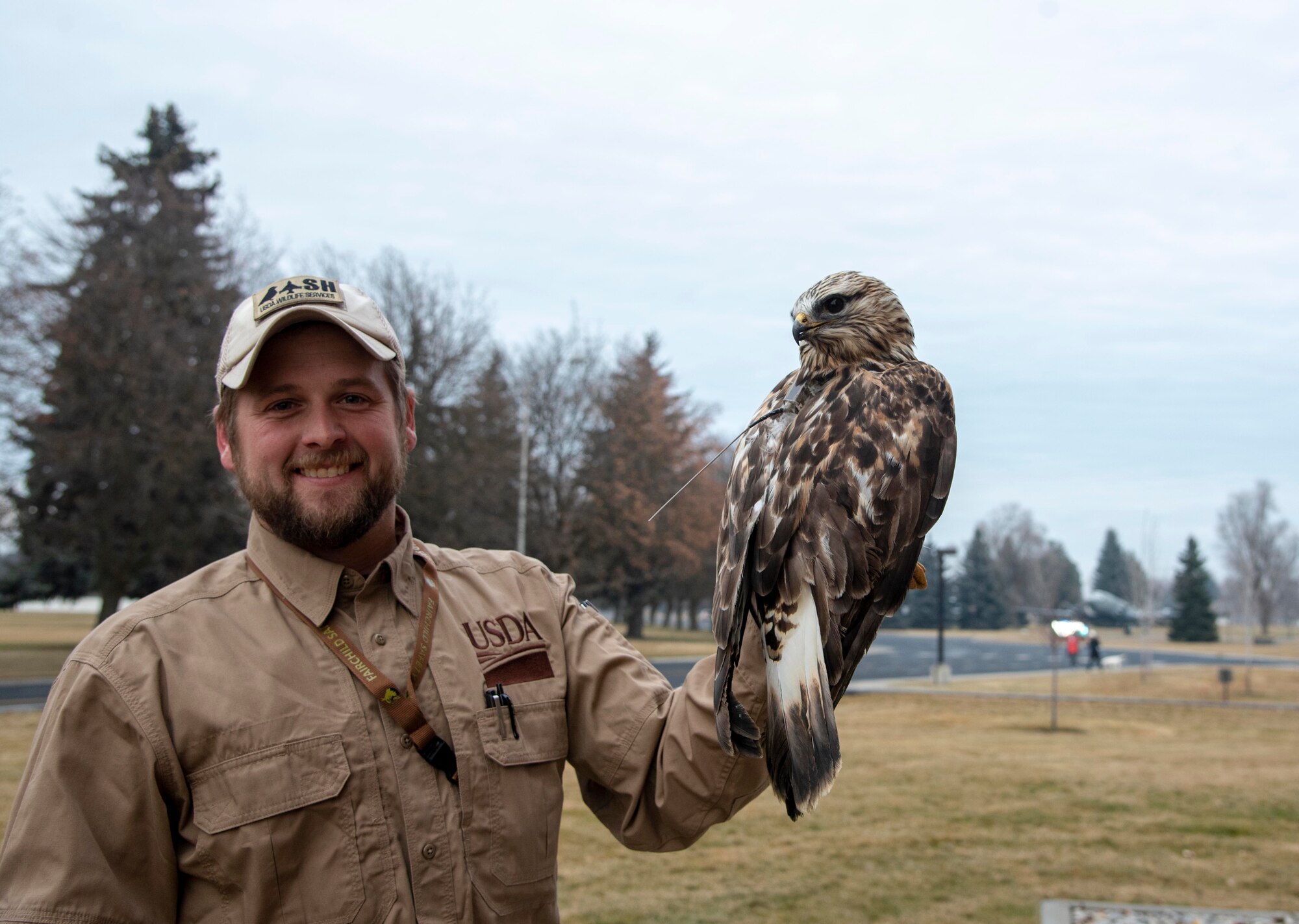 Carl Frey, United States Department of Agriculture wildlife biologist, poses for a photo with a captured rough-legged hawk at Fairchild Air Force Base, Washington, Dec. 6, 2019.