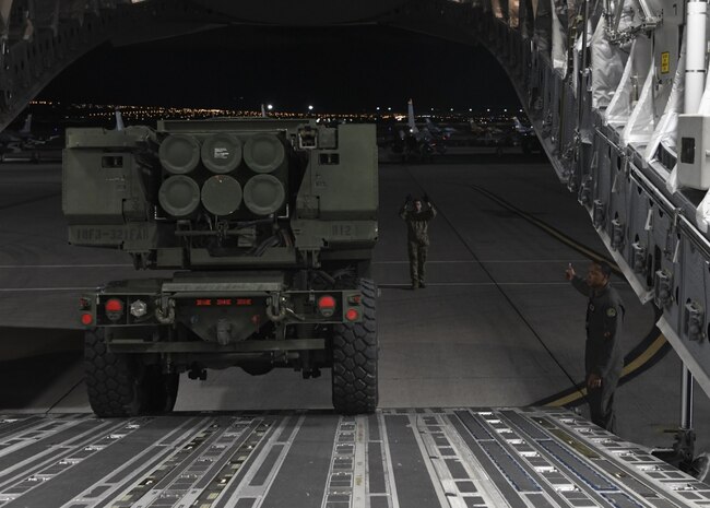 A vehicle is driven out of an aircraft onto a flightline.