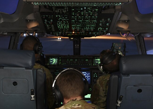 Three people sit in the cockpit of an aircraft.