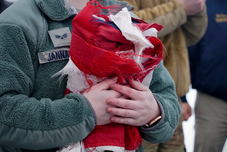 Senior Airman Breanna Jannarone, base honor guardsman, clutches an unserviceable U.S. flag to her chest during a ceremonial flag burn Dec. 7, 2019, on Grand Forks Air Force Base, North Dakota. Nearly 50 tattered, worn or faded flags from the local community were burned during the ceremony, conducted jointly by base honor guard and the local American Legion Post 6. (U.S. Air Force photo by Senior Airman Elora J. Martinez)