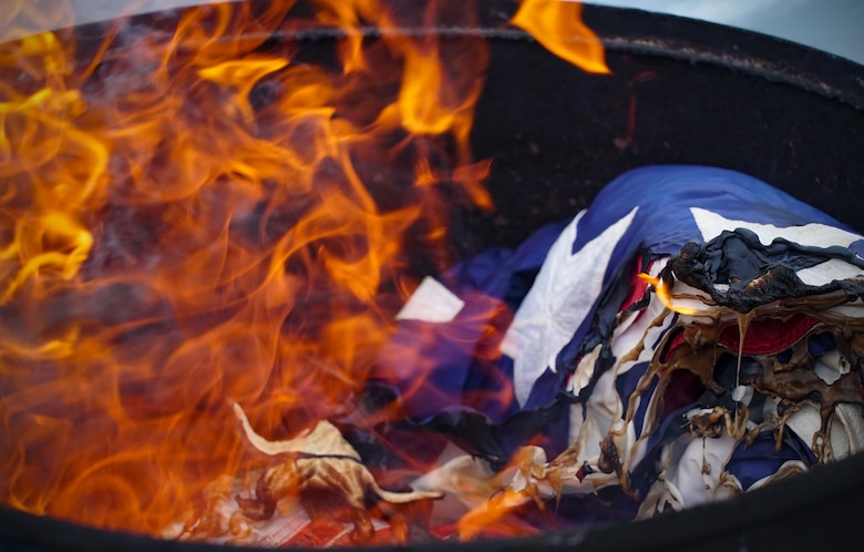 An unserviceable U.S. flag burns during a ceremonial flag burn Dec. 7, 2019, on Grand Forks Air Force Base, North Dakota. The American Legion Post 6 in Grand Forks worked alongside base honor guardsmen to burn nearly 50 worn, faded and otherwise unserviceable flags with dignity, and remembered the symbolism the flags offered during their lifetime flying over the local community. (U.S. Air Force photo by Senior Airman Elora J. Martinez)
