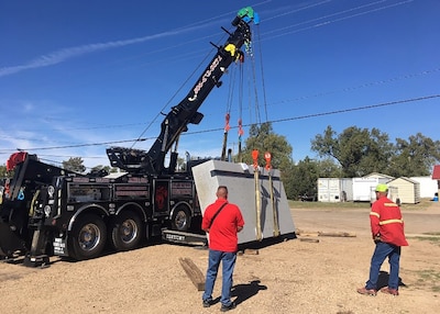 Two people look at granite slab suspended by cable as it is moved into position