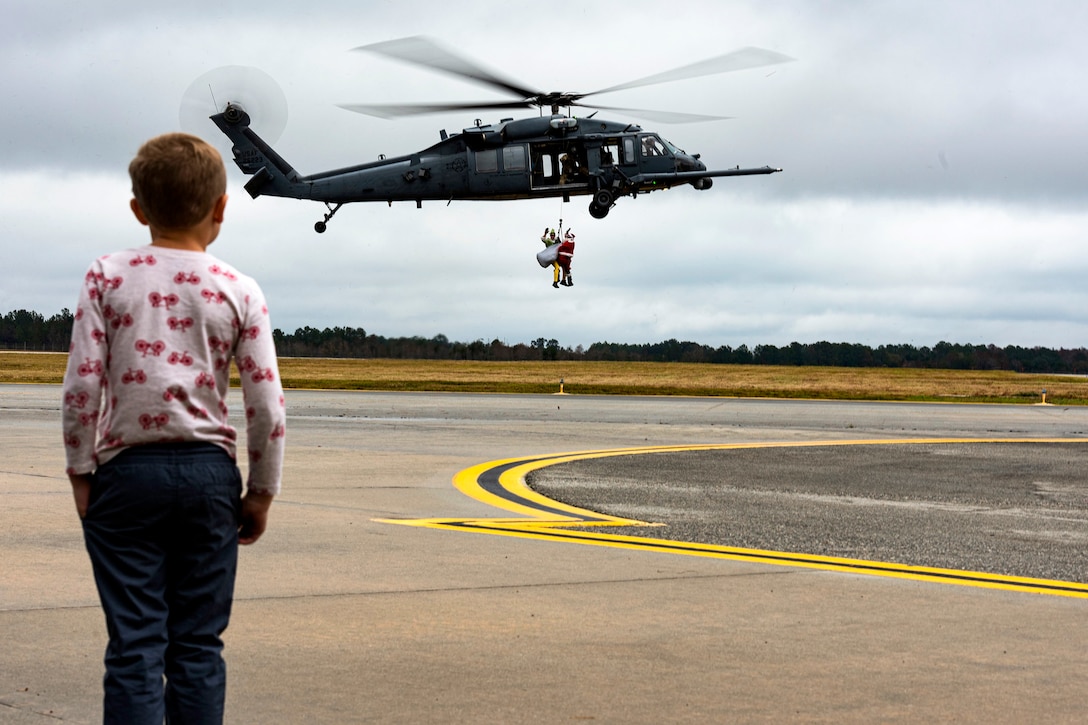 A child watches as Santa and his elf are lowered from a helicopter.