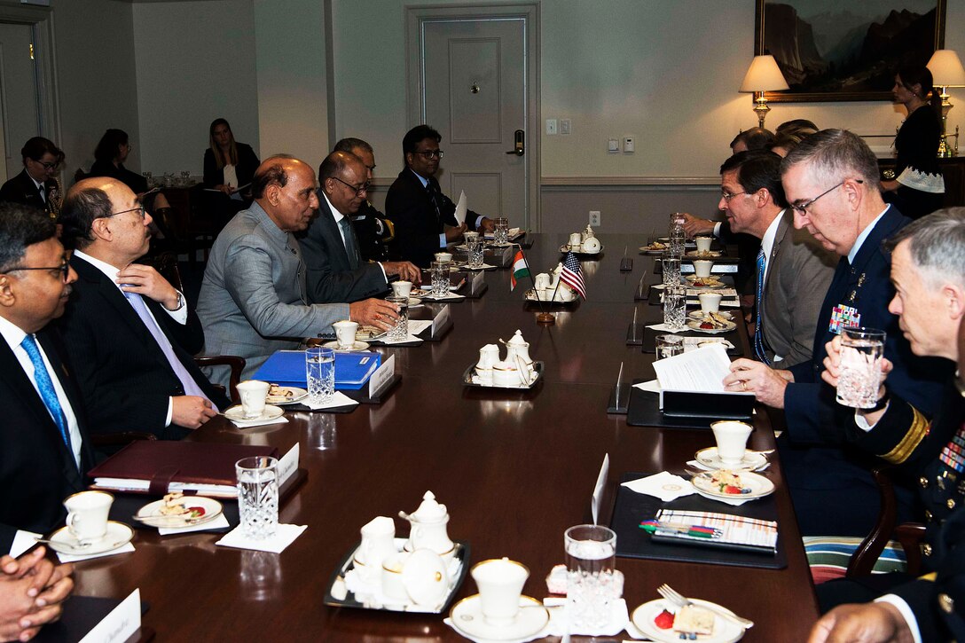 A group of military and civilian leaders meet around a table.