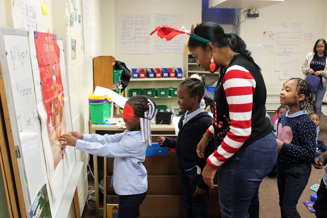 A DLA Troop Support volunteer helps children play games during the annual Children’s Holiday Party Dec. 12, 2019 in Philadelphia.